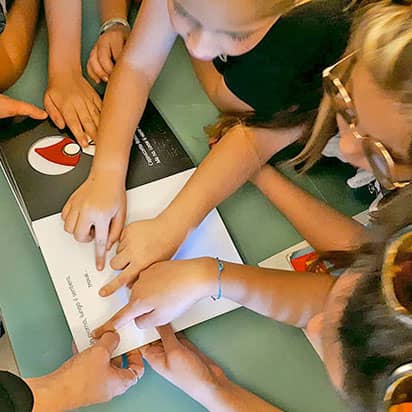 Fin. A moins que... Des enfants lisant un livre tactile avec leurs doigts