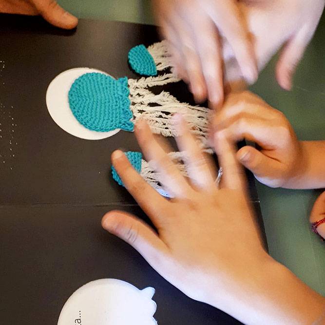 Les enfants explorent avec leurs doigts une page du livre tactile Une histoire imprévisible